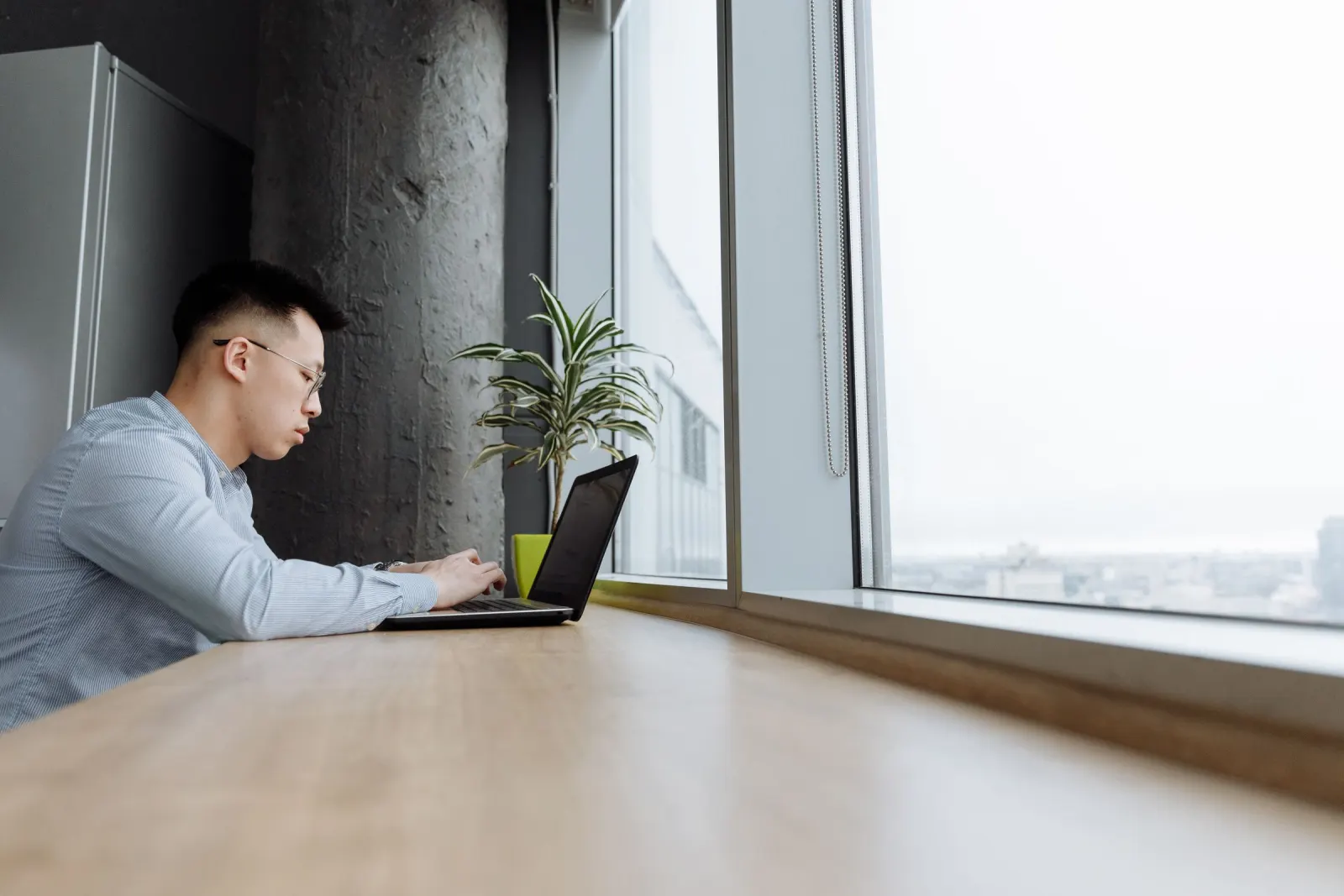 Person working on a laptop by an office window