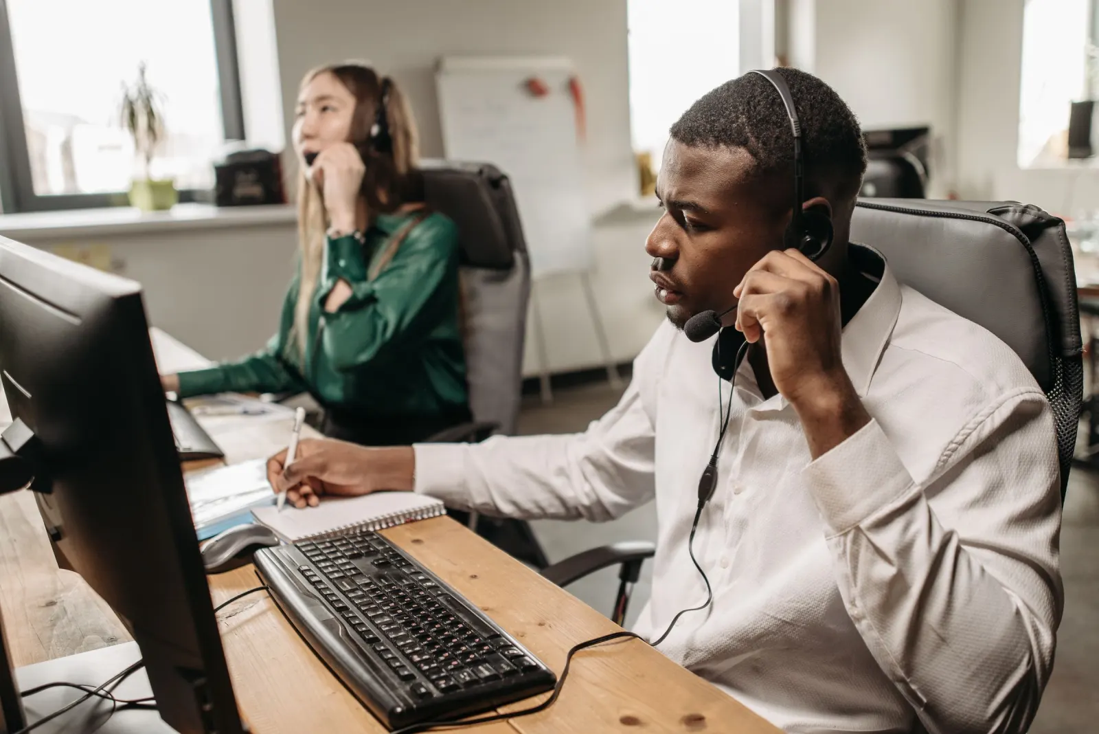Two agents on headset calls in an office